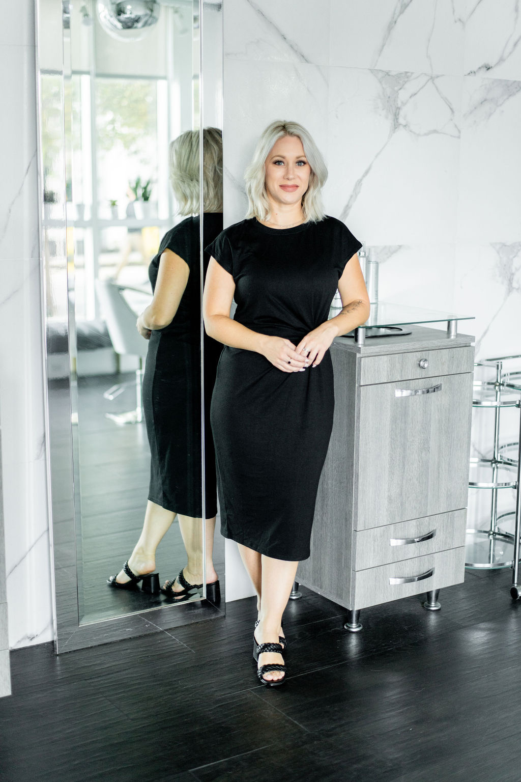 Kasey standing beside a mirror in the salon